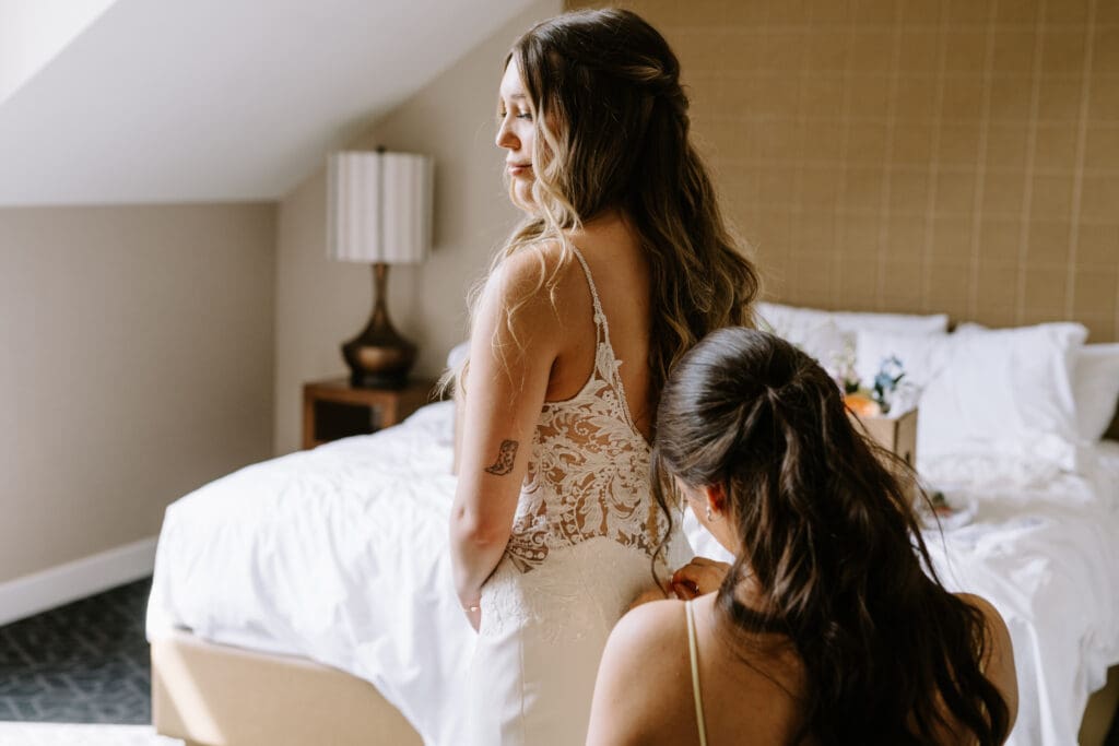 A bridesmaid zips up a bride's wedding gown at the Malcolm Hotel in Canmore